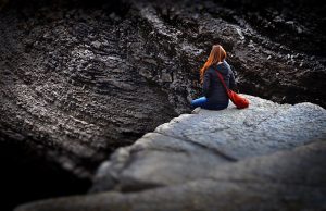 Woman sitting alone on rock