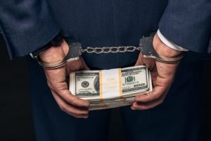 Man in formal wear in handcuffs holding money