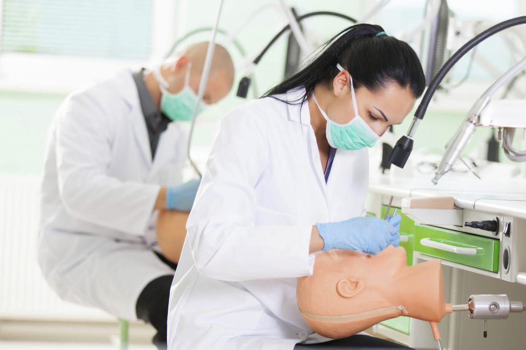 Female dental student practicing skills on dummy