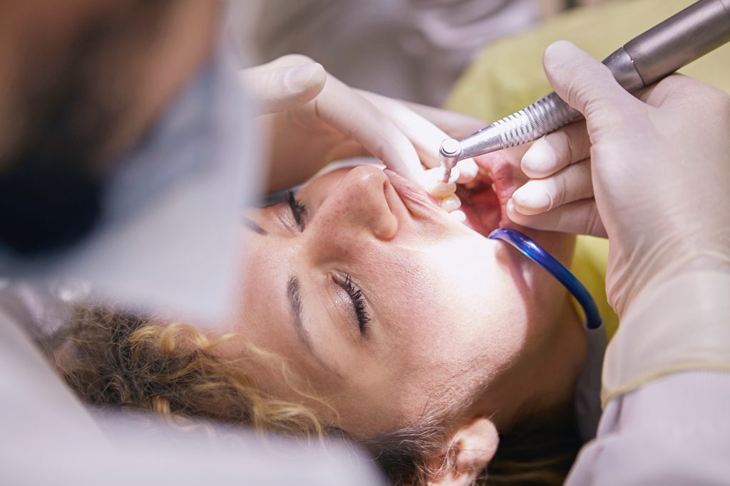 Male dentist performing dental work on female patient