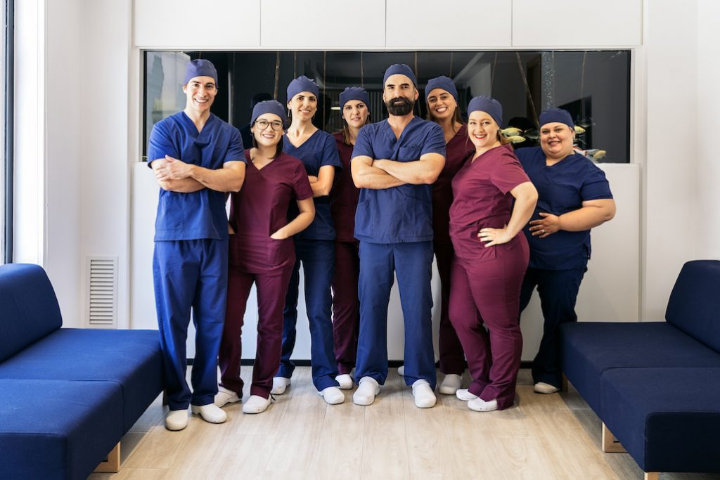 A group of smiling dentists posing for a photo in their dental office lobby